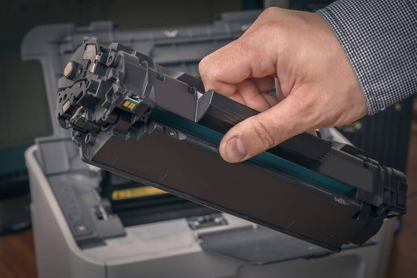 De mens vervangt zwarte cartridge in een laserprinter - Foto, afbeelding