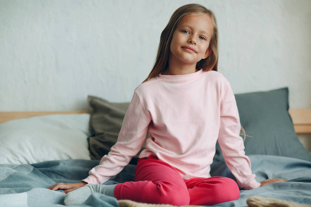 Smiling portrait of little girl sitting on bed. - Foto, Bild