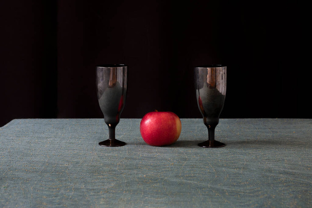 On the table are glasses with an apple. The apple is red. The table is gray. Horizontal frame. - Photo, Image
