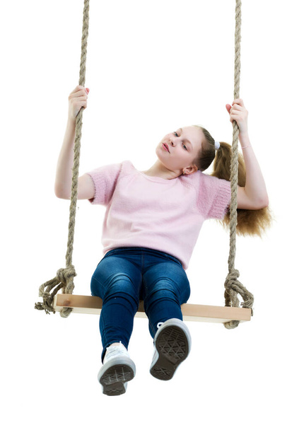Beautiful teen school girl swinging on a swing. Concept summer vacation. - Foto, afbeelding