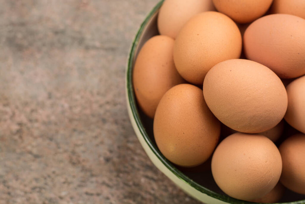 Brown farmers cage-free chicken eggs in bowl, close up copy space - Фото, изображение