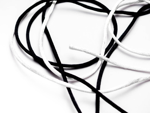 O conceito da matéria das vidas negras. Um nó com um fio branco e um fio preto contra um fundo branco
 - Foto, Imagem
