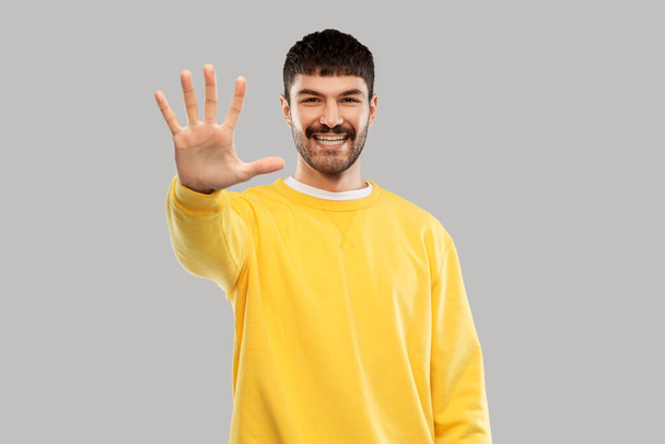 smiling young man showing his hand or five fingers - Фото, зображення