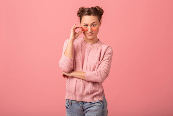 young pretty stylish smiling flirty looking in camera woman in pink sweater and sunglasses isolated on pink studio background - Φωτογραφία, εικόνα