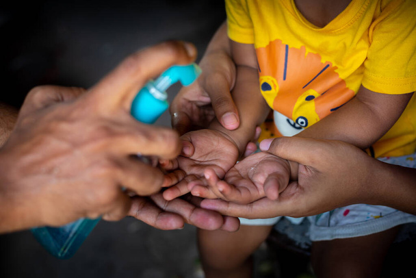 Uma criança está aprendendo a limpar as mãos com gel de limpeza líquido. Para evitar o coronavírus, esfregar as mãos com sabão é uma maneira especializada de parar a propagação do coronavírus
. - Foto, Imagem