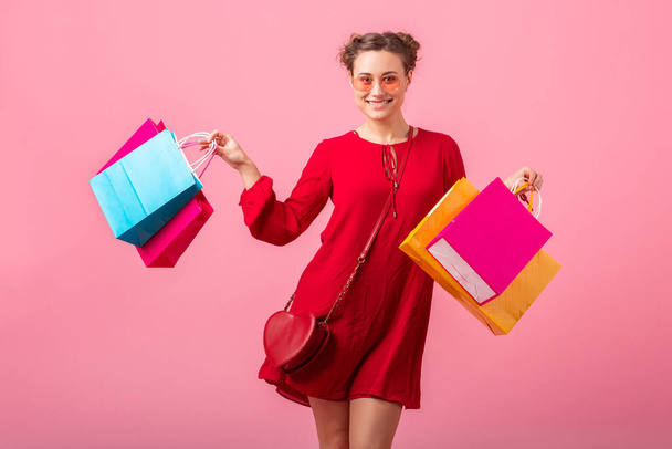 attractive happy smiling stylish woman shopaholic in red trendy dress holding colorful shopping bags on pink studio background isolated, sale excited, spring summer fashion trend - Фото, изображение