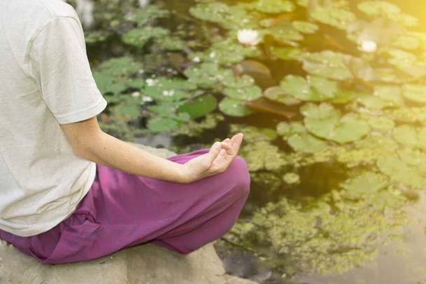 Um belo budista está meditando perto de um lago com lírios
 - Foto, Imagem