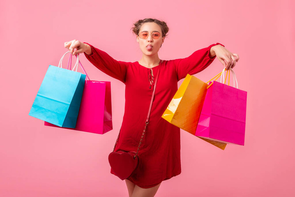 attractive happy funny emotion stylish woman shopaholic in red trendy dress holding colorful shopping bags on pink studio background isolated, sale excited, spring summer fashion trend - Фото, изображение