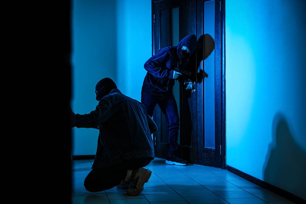 Dangerous criminals with gun and crow bar intruding into apartment - Valokuva, kuva