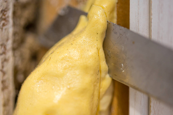 Makrobild eines Schneiders, der überschüssigen Polyurethanschaum schneidet, wenn er Türdichtungen versiegelt - Foto, Bild
