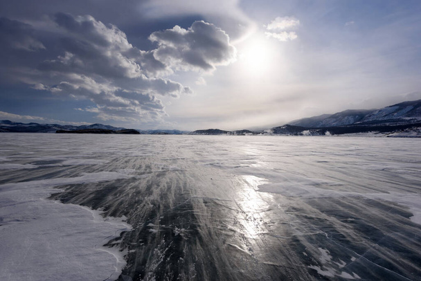 Beaux nuages sur la surface de la glace et la dérive de neige venteuse par une journée givrée. Lac Baïkal gelé
. - Photo, image