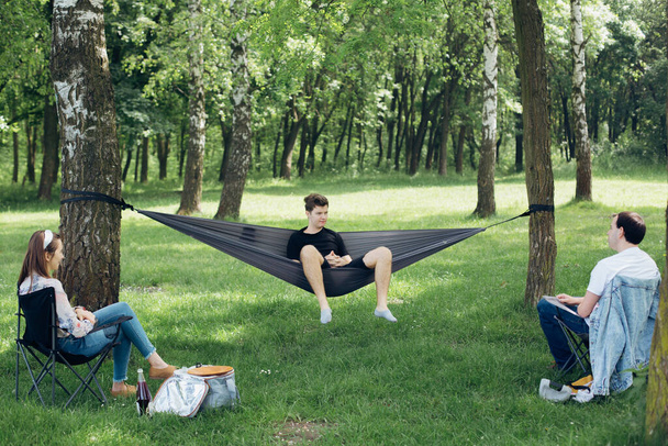 Social distancing. Small group of people enjoying picnic time in accordance with social distancing in summer park. Safety gatherings in new world. - Fotografie, Obrázek