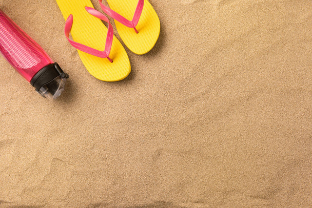 Top view flip flops and water bottle with copy space. Traveler accessories on sand. Travel vacation concept. Summer background. Border composition made of towel - Foto, Imagen