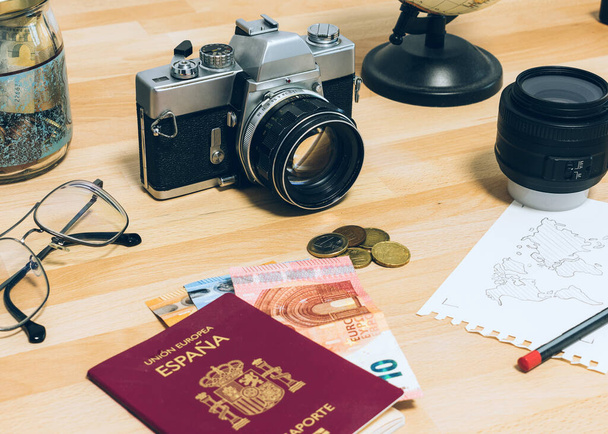 Φωτογραφική μηχανή, διαβατήριο, χρήματα, γυαλιά, σημειωματάριο με παγκόσμιο χάρτη, φακό και υδρόγειο. Ταξιδιωτική εικόνα έννοια: ταξιδιωτικά αξεσουάρ. - Φωτογραφία, εικόνα