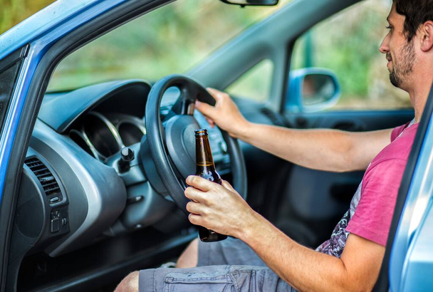 Man die alcohol drinkt terwijl hij in een auto rijdt - Foto, afbeelding