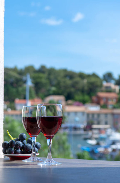 Zwei Weingläser mit Rotwein serviert mit roter Traube auf der Außenterrasse an einem sonnigen Sommertag - Foto, Bild