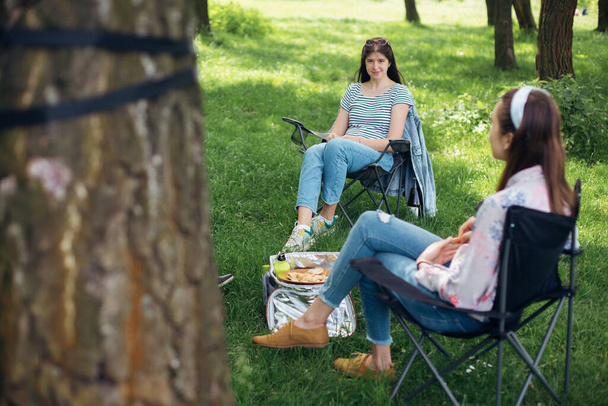 Distanze sociali. Piccolo gruppo di giovane donna che si gode una conversazione al picnic con la distanza sociale nel parco estivo. Attività per il tempo libero insieme in nuovi incontri normali e di sicurezza
 - Foto, immagini