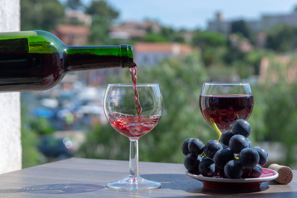 Офіціант поливає червоне вино на терасі кафе в сонячний літній день у Франції. - Фото, зображення