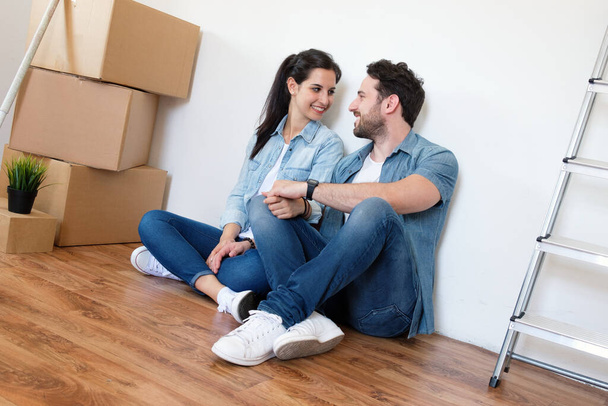Portrait of cheerful young couple sitting in new house - Photo, Image