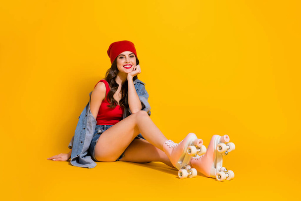 Full body photo of positive cheerful youth teen girl fit roller skater sit floor enjoy free time weekend wear student style headwear tank-top denim isolated over bright color background - Foto, afbeelding