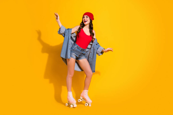 Full size photo of cheerful funky teen youth student girl enjoy spring free time weekend roller skated ride wear red headwear jeans singlet isolated over bright color background - Foto, immagini