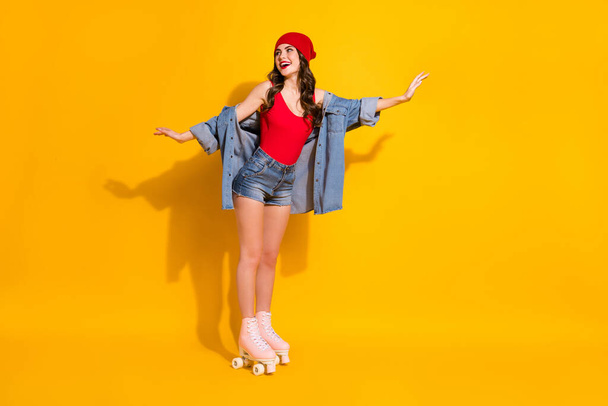 正陽気な率直なコンテンツのフルサイズの写真友人とティーン女の子乗りローラースケートは、明るい色の背景の上に隔離された赤いヘッドウェアのシングルジーンズを着用コピースペースをお楽しみください - 写真・画像