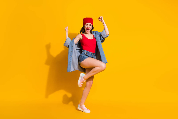 Full length photo of delighted cheerful youth girl celebrate discount lottery win raise fists scream yeah wear red headwear tank-top denim isolated over bright color background - Фото, зображення