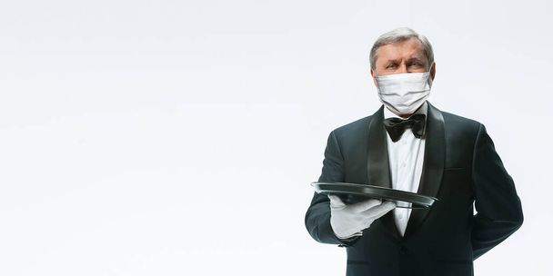 Elegance senior man waiter in protective face mask on white background. Flyer with copyspace. - Fotó, kép