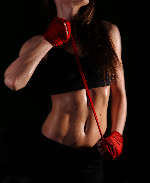 Female fitness body wet after workout in the dark. Sport motivation image. Hand wrist wraps - Photo, Image