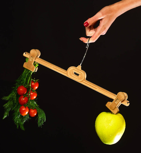 La mano femenina sostiene la percha con frutas y verduras en las puntas - Foto, Imagen