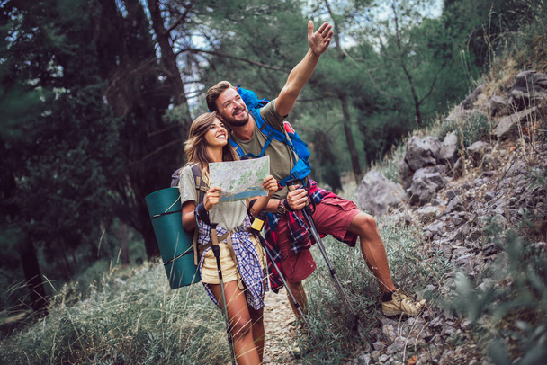 Couple hiking trough forest. Using map to get good direction. - Fotoğraf, Görsel