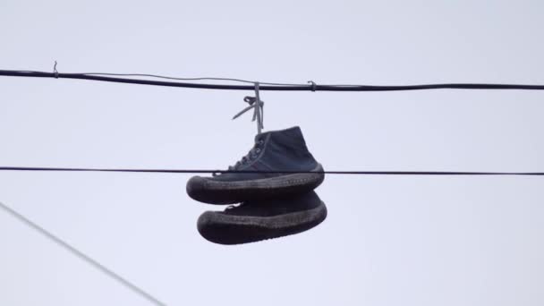 zapatillas colgando de cables negros contra el cielo - Imágenes, Vídeo