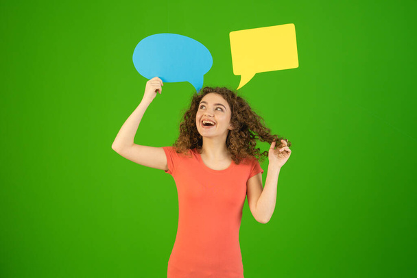 Жінка посмішки стоїть з діалоговими знаками на зеленому тлі
 - Фото, зображення