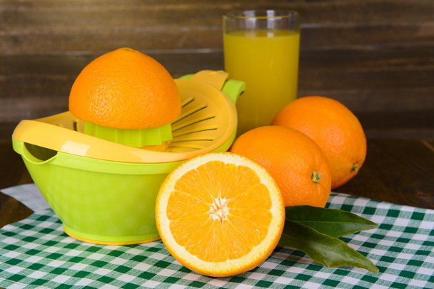 Citrus press and oranges on table on wooden background - Fotoğraf, Görsel