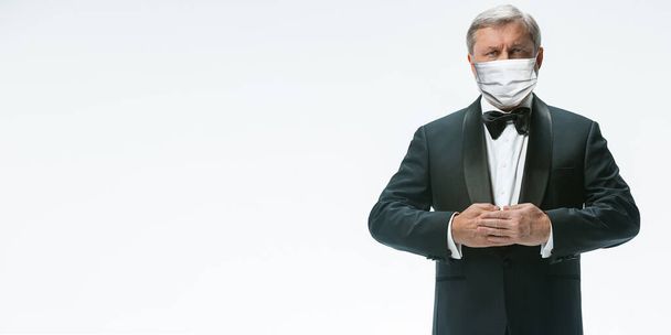 Elegance senior man waiter in protective face mask on white background. Flyer with copyspace. - Zdjęcie, obraz