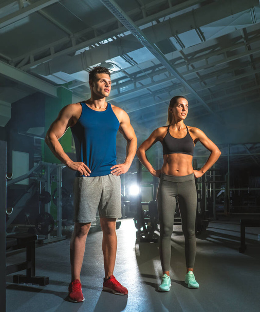 The sport couple stand in the gym on the bright light background - Φωτογραφία, εικόνα