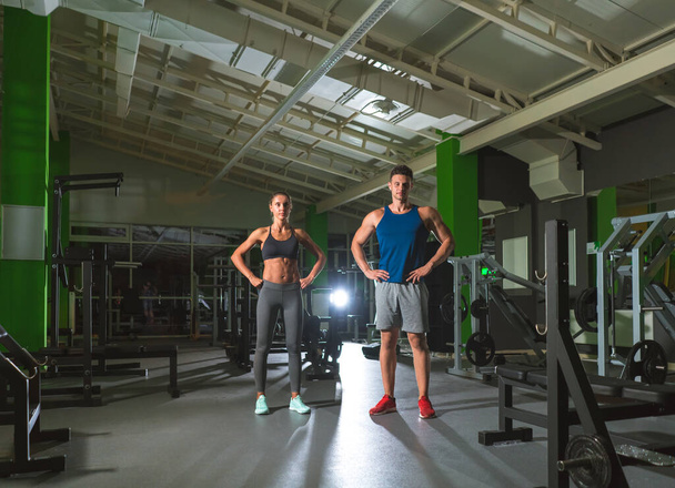 The sport couple stand in the modern gym on the bright light background - Fotó, kép
