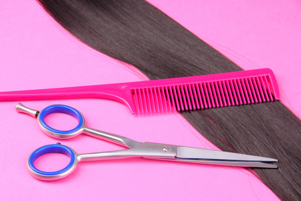 Long black hair with comb and scissors on pink background - Fotoğraf, Görsel