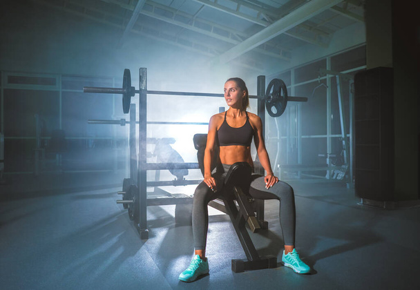 Die schöne Sportlerin sitzt im Fitnessclub - Foto, Bild