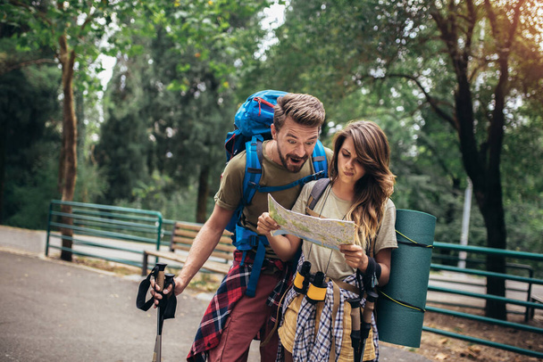 Couple hiking trough forest. Using map to get good direction. - 写真・画像