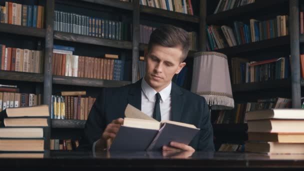 Geschäftsmann im klassischen Anzug sitzt in Bibliothek und liest Buch. - Filmmaterial, Video
