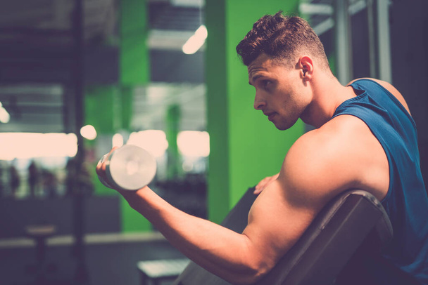 El deportista haciendo ejercicio bíceps con una mancuerna en el gimnasio
 - Foto, Imagen