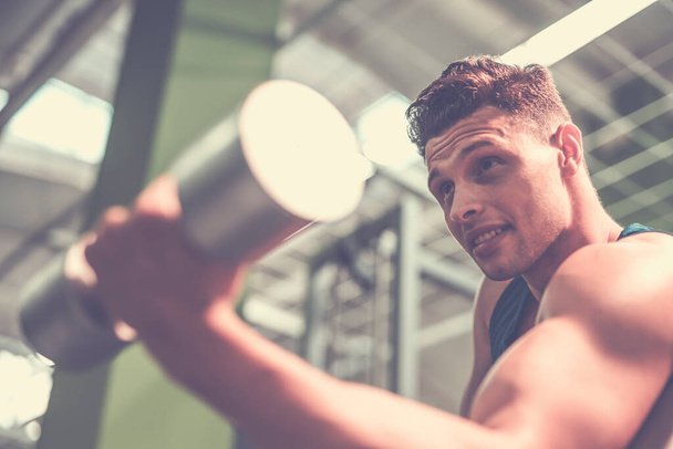 Ο αθλητής που κάνει άσκηση δικέφαλων με ένα αλτήρα στο γυμναστήριο - Φωτογραφία, εικόνα