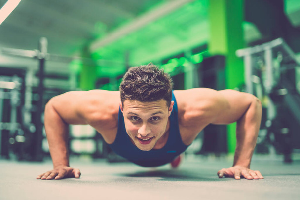 Ο χαρούμενος αθλητής κάνει push up άσκηση στο γυμναστήριο - Φωτογραφία, εικόνα