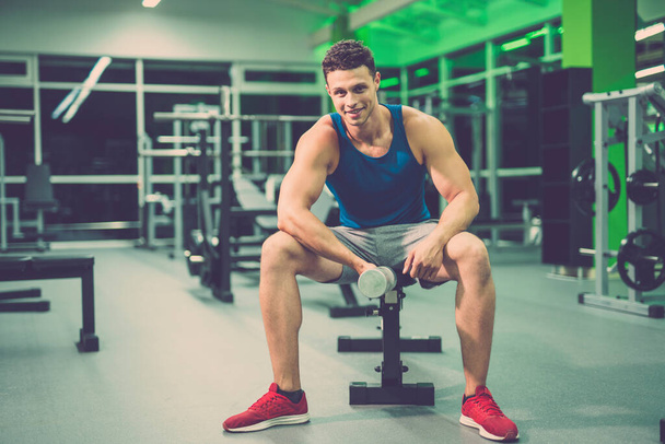 El hombre feliz haciendo ejercicio con una mancuerna en el gimnasio
 - Foto, imagen
