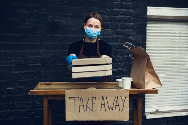 Woman preparing drinks and meals, wearing protective face mask and gloves. Contactless delivery service during quarantine coronavirus pandemic. Take away only concept. - Fotó, kép