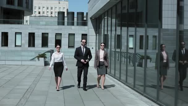 Three business people walking on camera in business clothes and sunglasses outdoors near office building. Professional people going back from coffee break. Business concept. Prores 422 - Filmati, video