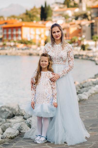 Italy, Lake Garda.Stylish Mother and daughter on the shores of lake Garda in Italy at the foot of the Alps. mother and daughter in Italy. - Foto, afbeelding