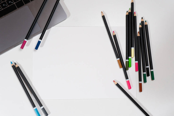 Papel en blanco sobre la mesa con portátil y lápices
 - Foto, imagen
