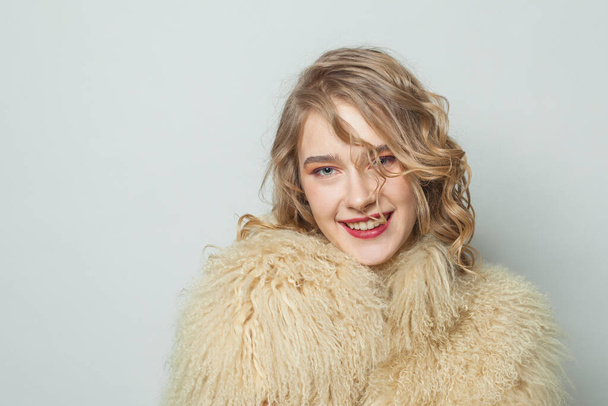 Portrait of happy woman in eco friendly faux fur coat on white background - Photo, image